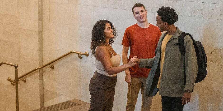 2 men and a women standing together in a group one of the men is shaking hands with the women