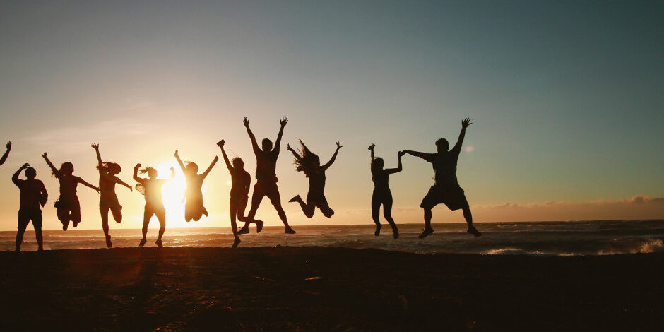 silhouetted group of people jumping up in the air and looking at the sunset