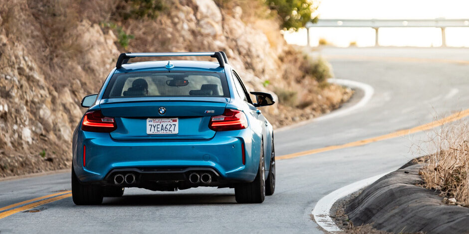 blue car with California plates driving on a winding road