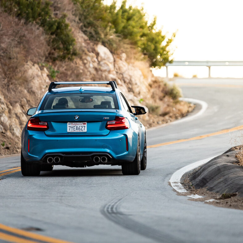 blue car with California plates driving on a winding road